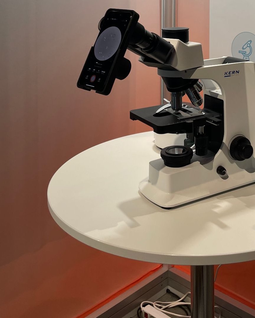 An iPhone mounted on a precision adapter attached to a standard light microscope